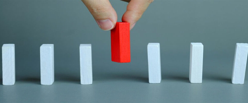 Red domino being chosen in a row of white standing out choosing